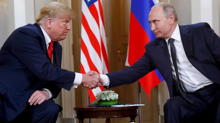 President Donald Trump shakes hands with Russian President Vladimir Putin...