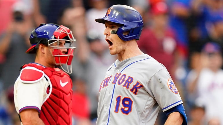Mets' Mark Canha, right, reacts past Philadelphia Phillies catcher J.T....
