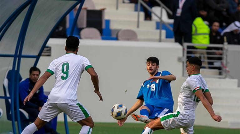 Kuwait's Mahdi Hussain, center, fights for the ball against Iraq's...