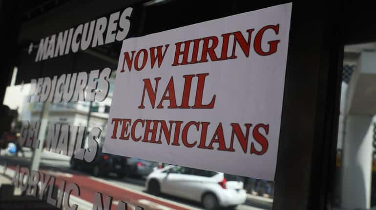 A help wanted sign hangs on a window of business...