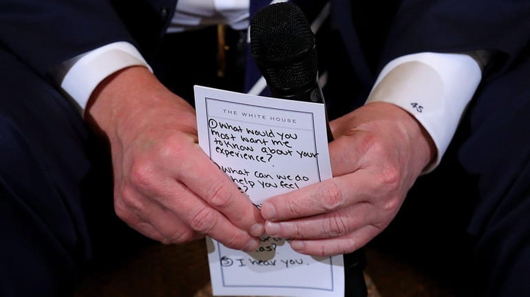 President Donald Trump holds his notes while hosting a listening...