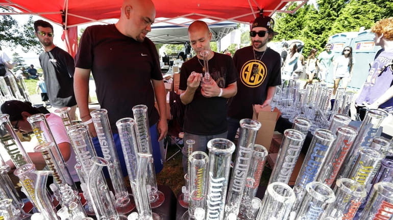 Vendors look over their display of glass bongs at the...