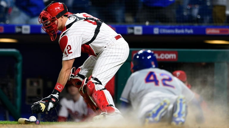 Phillies catcher J.T. Realmuto, left, is unable to make a...