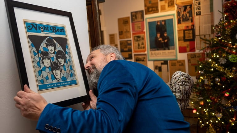 Ron Seifried hangs some Beatles artwork.