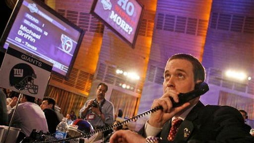 A Giants draft representative talks on the phone before making...