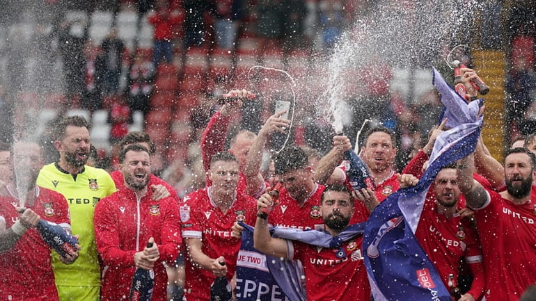 Wrexham players on the pitch celebrate promotion to League One...