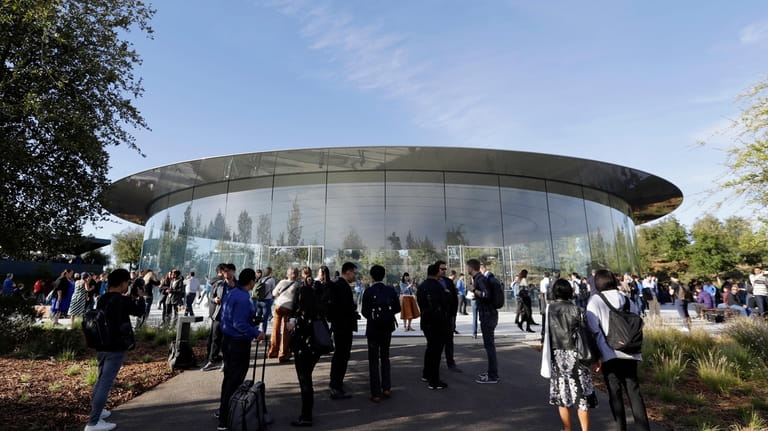 File - People stand outside of the Steve Jobs Theater...
