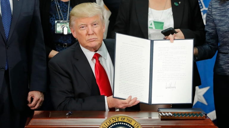 President Donald Trump holds up the executive order for border...