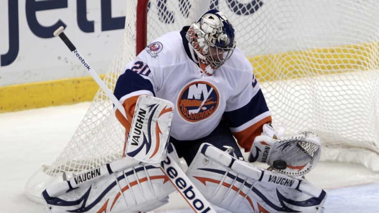 New York Islanders goalie Evgeni Nabokov blocks a shot by...