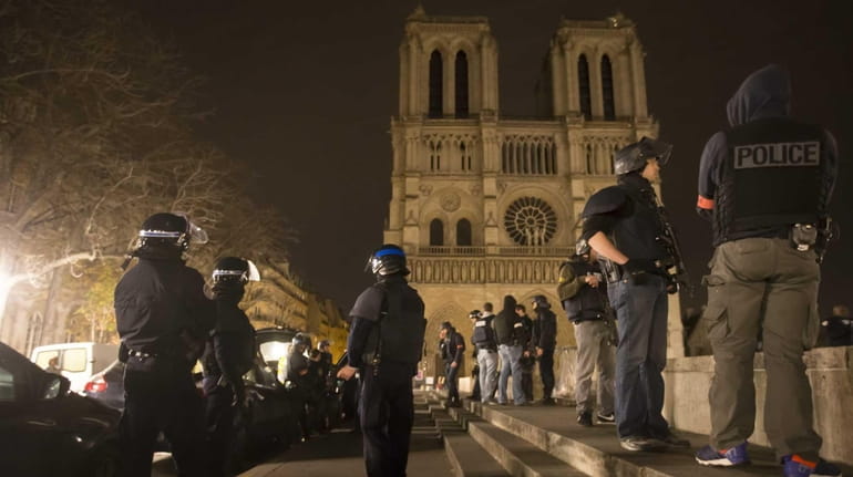 Armed police officers patrol on foot around Notre Dame Cathedral...