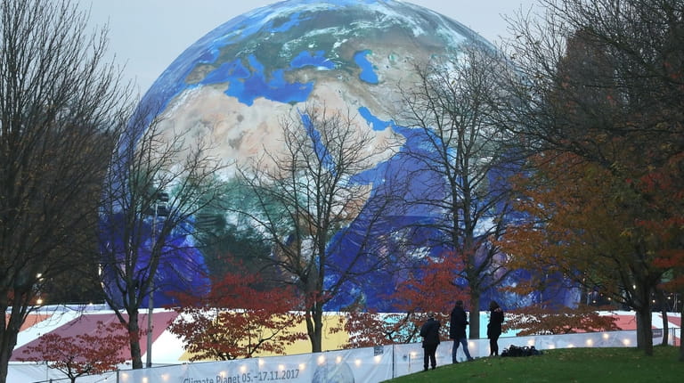 People walk past the "Climate Planet," an exhibition and film...
