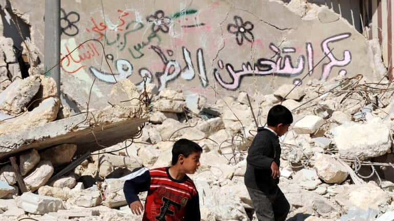 Syrian children walk past destroyed buildings in the northern city...