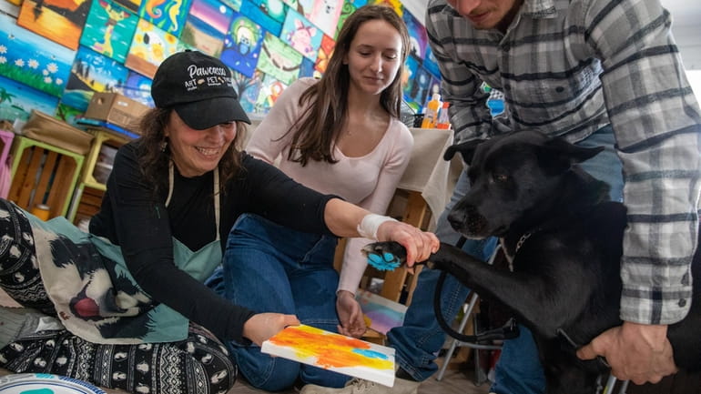 Owner Barbara Martorelli, left, makes dog paw art with Alli...