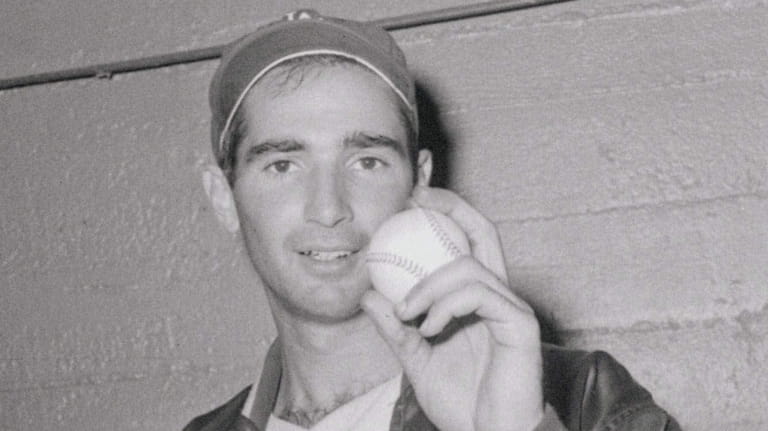 Los Angeles Dodger pitcher Sandy Koufax shows off one of...
