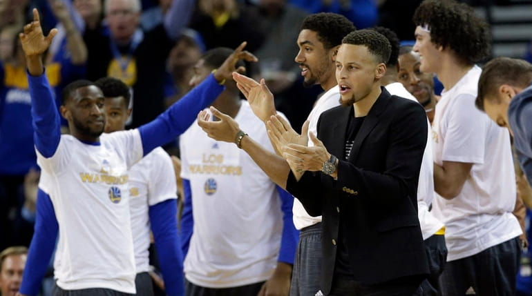 The Golden State Warriors' Stephen Curry, right in black, watches...