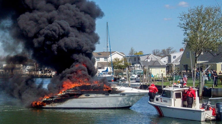 A Coast Guard boat sits near a flaming private craft...