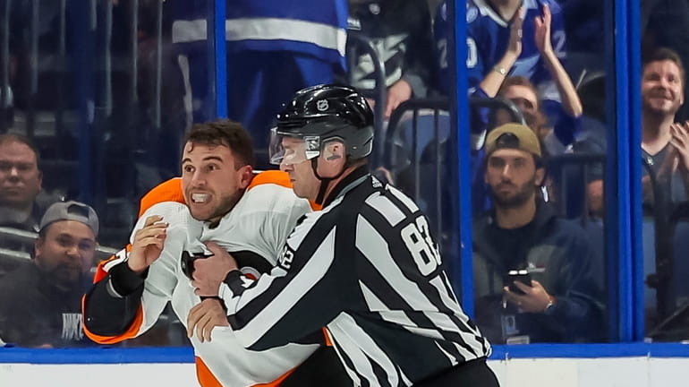 Philadelphia Flyers' Tony DeAngelo is held back by linesman Ryan...