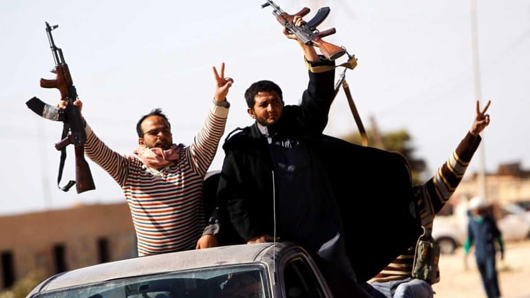 Libyan rebels cheer as they advance in a truck outside...