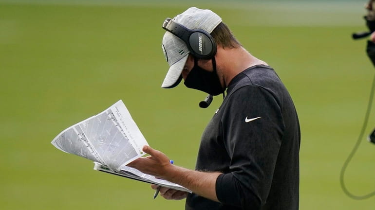 Jets head coach Adam Gase looks at copies of plays...