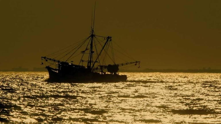 Off Long Beach, Long Island, a lone fishing trawler heads...