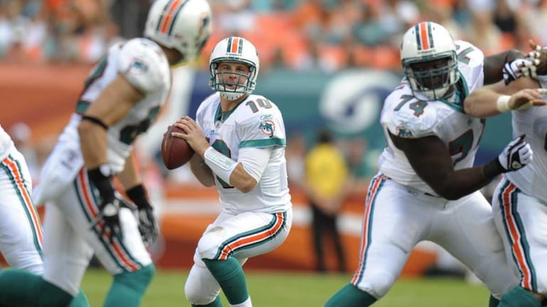 Miami Dolphins quarterback Chad Pennington, center, drops back to pass...