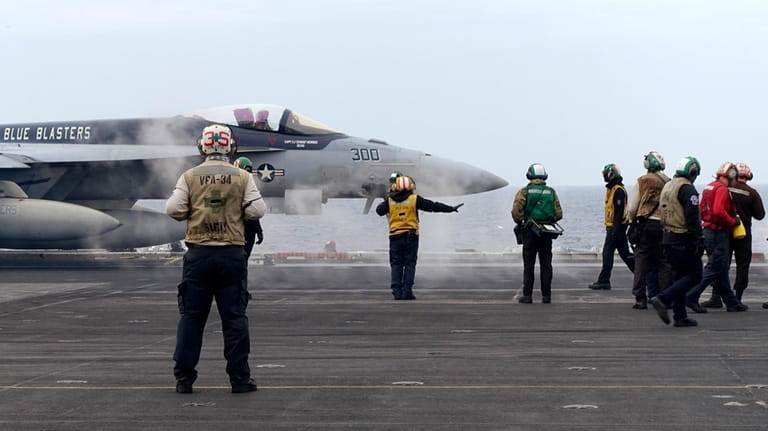 A F-18E fighter jet prepares to take off from USS...