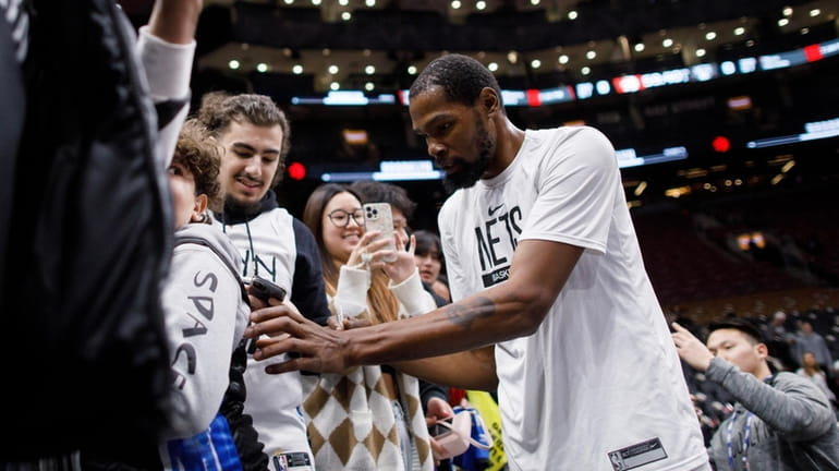 Kevin Durant #7 of the Nets signs autographs as he...
