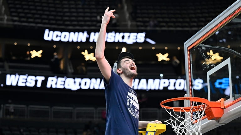 UConn's Alex Karaban celebrates while cutting down the netting from...