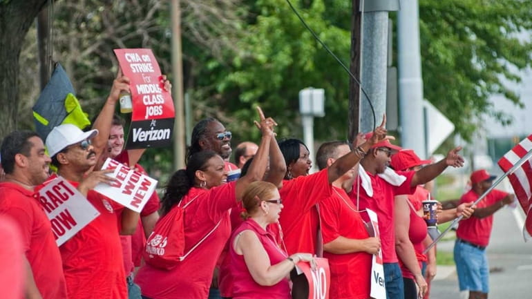 Verizon employees yell across the street at non-striking employees leaving...
