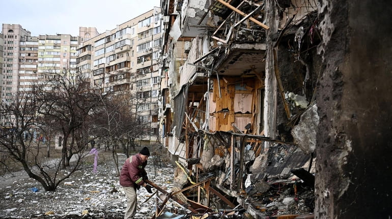  A man clears debris at a damaged residential building in a...