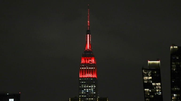 The Empire State building is lit in red and white...