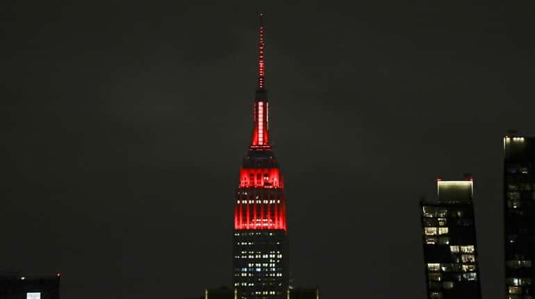 The Empire State building is lit in red and white...