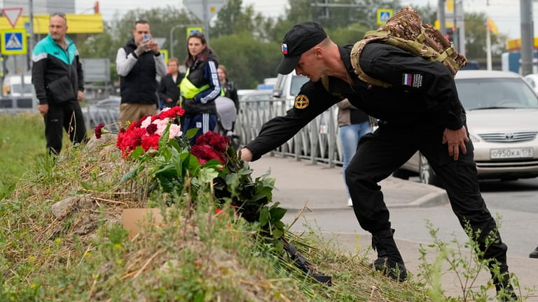A man lays flowers at an informal memorial next to...