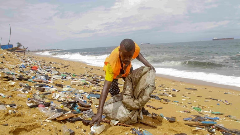 A trash collector picks up plastic along Port Bouet beach...