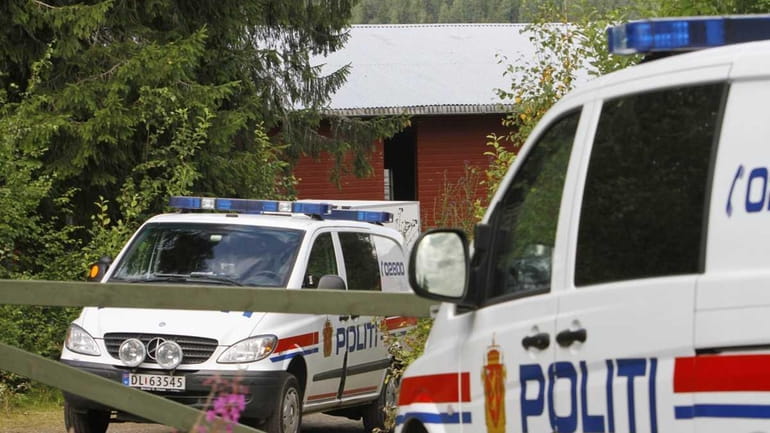 Police cars sit in front of the farm of Anders...