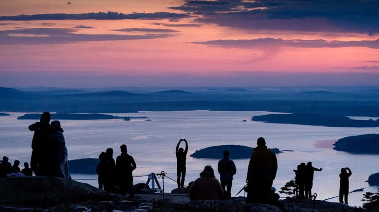 Early-rising visitors to Acadia National Park await the sunrise on...