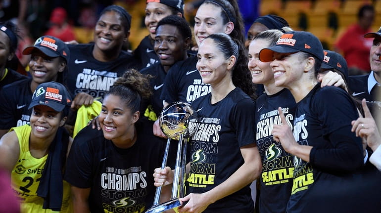 Seattle Storm guard Sue Bird, holding trophy, and others pose...