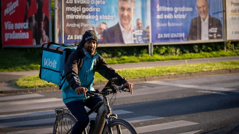 A delivery man rides a bicycle in front of election...