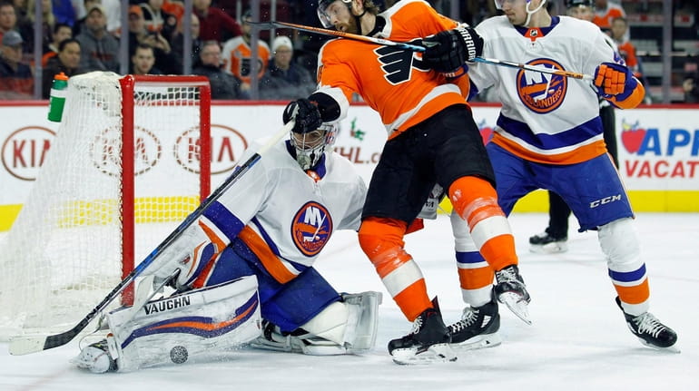 New York Islanders goalie Thomas Greiss, left, blocks the puck...