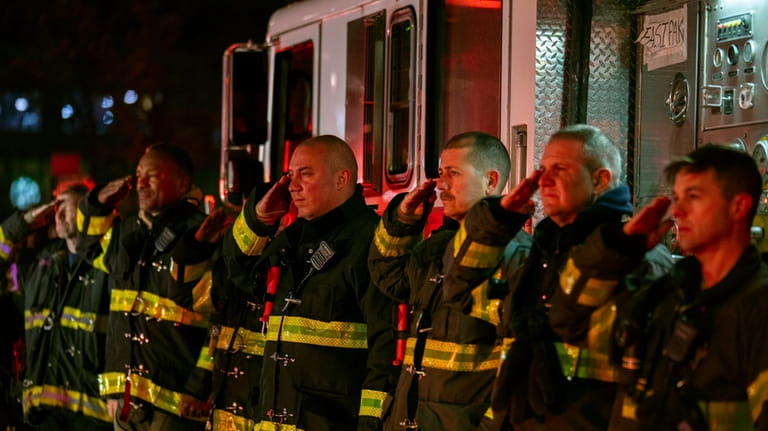 Firefighters salute as the ambulance transporting the body of New...