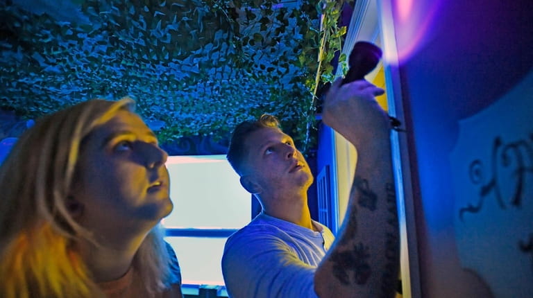 Paige and Sean Smith use a black-light flashlight to search...