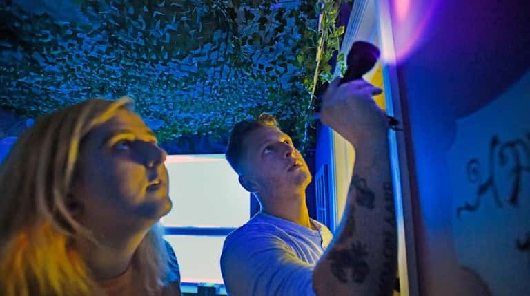 Paige and Sean Smith use a black-light flashlight to search...