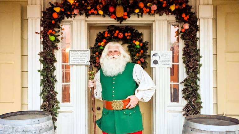 Kris Kringle stands on the porch of a historic building at...