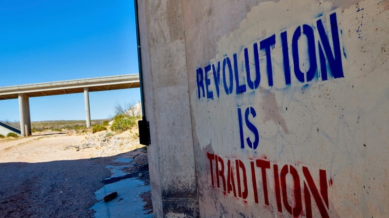 "Revolution is Tradition" appear freshly stenciled on a cement wall,...