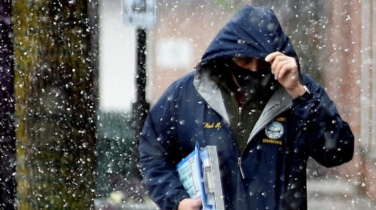 Snow falls as a man walks in Patchogue Thursday.