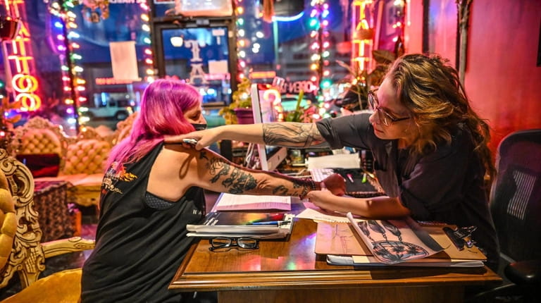 Tattoo artist and shop owner Cory Good consults with customer...