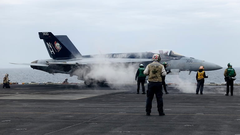 A F-18E fighter jet prepares to take off from USS...