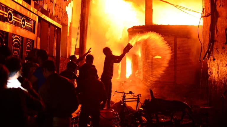 Firefighters and local people help to douse a fire in...