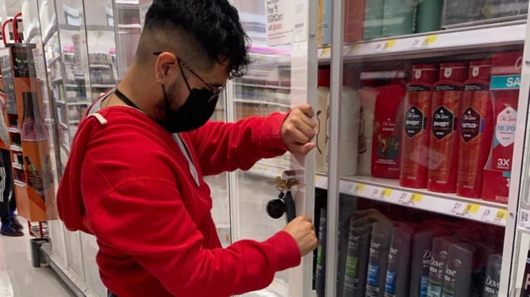 A Target employee locks personal hygiene items in new security shelving...