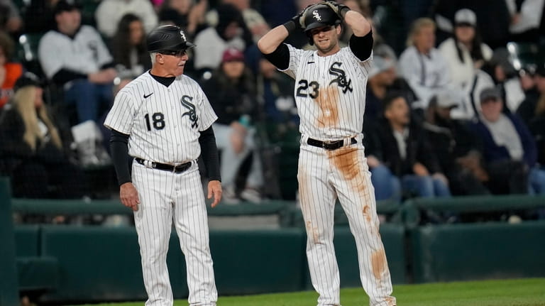 Chicago White Sox's Andrew Benintendi, right, stands next to third...